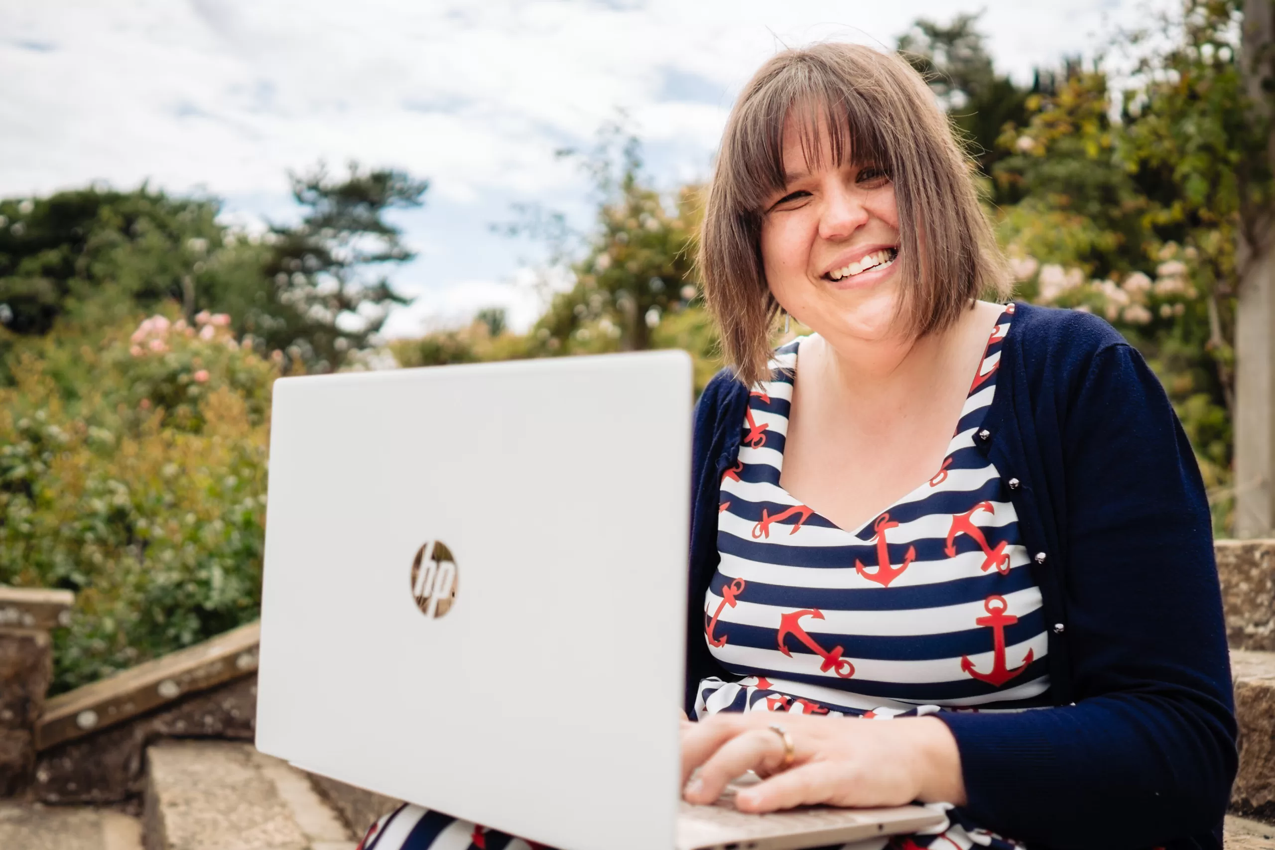 steph looking up from reading laptop whilst sitting on steps in garden
