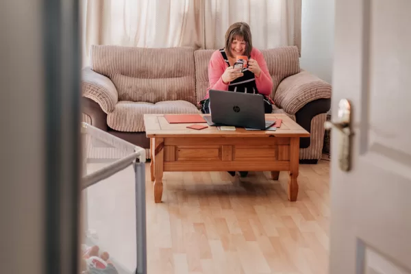 Looking from doorway at Steph smiling and reading her phone