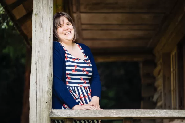 Steph leaning against fence post in cabin